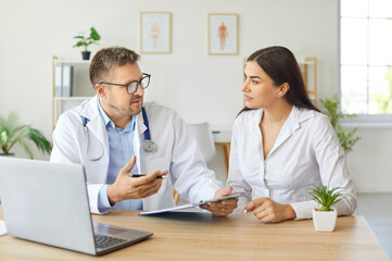 Woman patient receives consultation from a doctor or nurse in a hospital office. Healthcare professional offers medical advice, providing support and care during the patient visit to the physician.