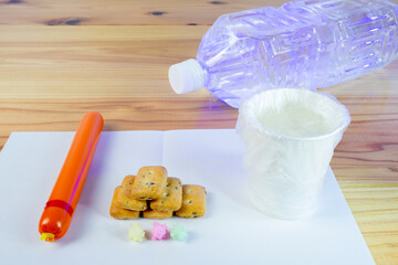 ビニール袋でカバーされた水が入った紙コップと避難所での一食の配給食料