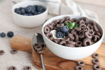 Bowl with chocolate cereal rings and berries on beige grunge background, closeup