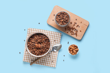 Bowls with tasty chocolate granola on blue background