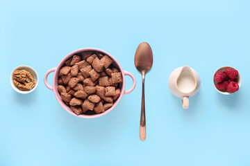 Bowl with tasty chocolate corn pillows on blue background