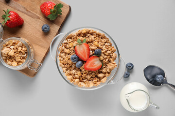 Bowl with tasty granola and berries on white background
