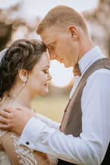 Obraz premium A tender close-up of a bride and groom touching foreheads outdoors, showing love and intimacy, with soft natural light during golden hour..
