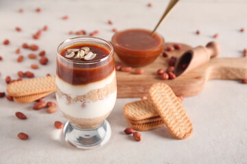 Glass with delicious peanut cheesecake on beige grunge background