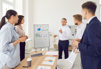 Male chief is conducting a meeting or presentation for a team of office workers. This business people gathering involves employees and staff, focusing on work related discussions and teamwork.