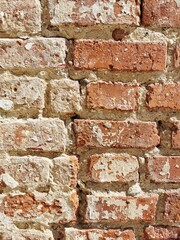 Close-up view of an aged brick wall with texture variations and weathered paint. Architectural vertical background