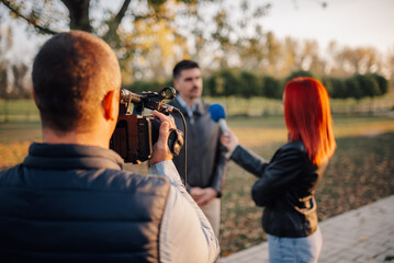Cameraman recording journalist interviewing businessman in park