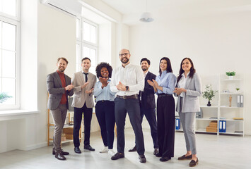 Group of a business multiethnic diverse people men and women looking cheerful at camera applauding...