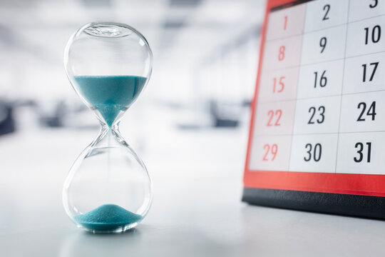 Hourglass and calendar on office desk important appointment date, schedule and deadline