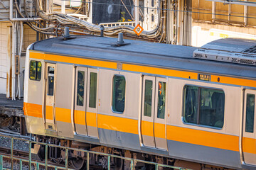 Trains, the outside of a Japanese train with orange color at daytime on the traintracks of Tokyo city in Japan.