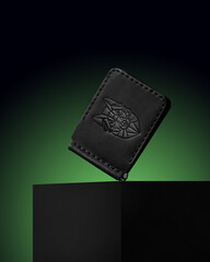 black men's wallet made of genuine leather on a green background, object photography, object photo of a wallet, men's accessories