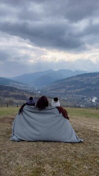 Friends enjoying a cozy moment while overlooking a mountain valley in winter