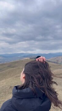 Exploring scenic hills wearing cozy winter attire in a cloudy landscape