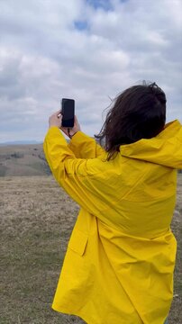 Woman capturing nature with a smartphone in a mountainous landscape