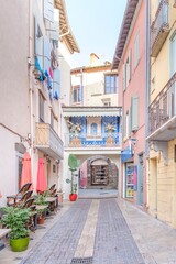 Charming Mediterranean Alleyway with Pastel Buildings and Cafe Terrace. Picturesque Street Scene in Collioure (Cotlliure), French Catalonia - Decorated Balcony and Stone Archway in Historic Town