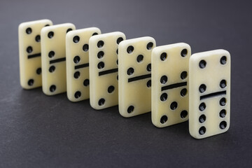 Domino tiles lined up in a perfect sequence on a dark green surface