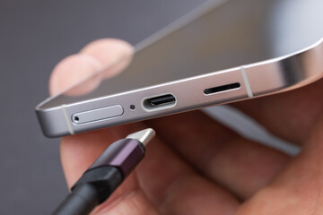 Charging a smartphone via a USB cable and a power supply. A black smartphone hanging with a usb...