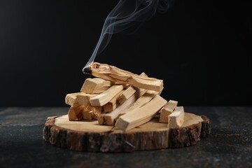 Palo santo sticks and smoldering one on dark table, closeup