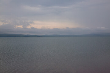 Natural background of lake water, sky and shore in the background