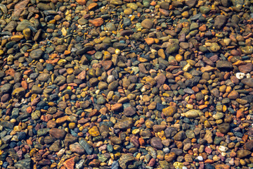 Stones on the river bottom under a layer of clean river water. Pebble texture. Ecology.