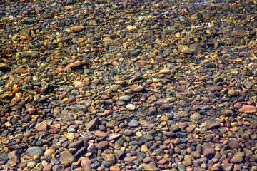 Stones on the river bottom under a layer of clean river water. Pebble texture. Ecology.