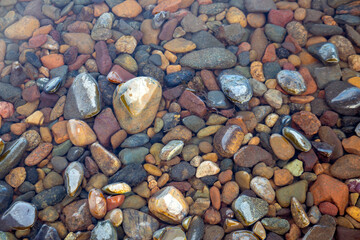 Stones on the river bottom under a layer of clean river water. Pebble texture. Ecology.