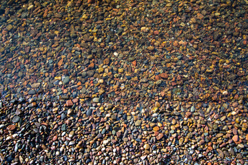 Stones on the river bottom under a layer of clean river water. Pebble texture. Ecology.
