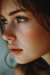 Fototapeta premium A close-up portrait capturing the delicate features of a young woman with soft freckles, expressive green eyes, and flowing brunette hair.