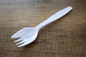 White plastic sporks on wooden background