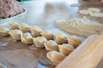 authentic photo of dumpling making at home. There is a dough on the table, flour and ground beef with onion for dumplings. High quality photo