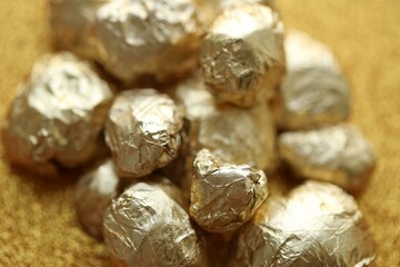 Small pile of golden nuggets on shiny gold glitter background