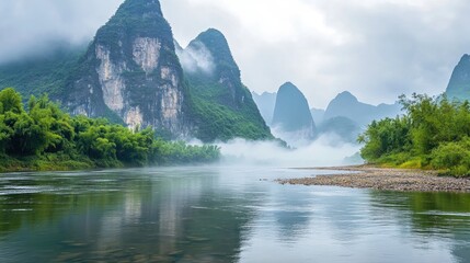 Serene river landscape with majestic mountains and fog on a cloudy day reflecting in tranquil waterçŽ¯å¢ƒä¸Žå£®ä¸½å±±è„‰çš„æ²³æµæ™¯è§‚