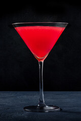 Cosmopolitan cocktail with vodka and cranberry juice in an elegant glass, on a black background