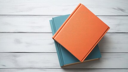 Fototapeta premium Colorful stack of books in orange and blue resting on a rustic white wooden table creating a cozy study atmosphere ideal for educational and literary concepts