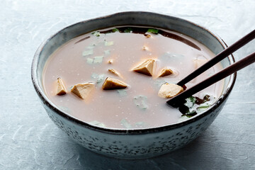 Eating tofu soup, Japanese cuisine. Miso soup with bean curd and green onions, a close-up with chopsticks