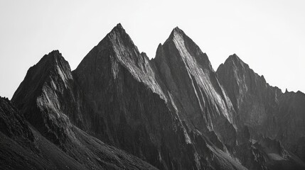 Obraz premium Majestic mountain peaks display their rugged beauty against a clear sky in a striking monochrome landscape photograph.