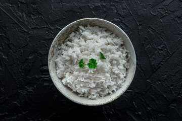 White rice, cooked. A bowl of boiled long grain rice, a simple side dish, with fresh parsley...