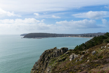 Panorama sur la baie de Morgat et la mer d’Iroise depuis les falaises, sous un ciel bleu ponctué de nuages.