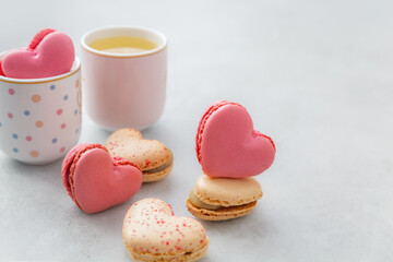 Cake macaron or French macaroon in heart shapes, two cups on grey background with copy space. French pastry made from egg whites. Culinary and cooking concept. Love