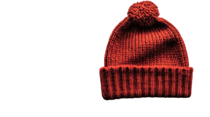 A cozy handmade red knit hat with a pom-pom resting on a plain background
