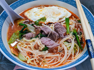 Noodle soup with beef and a fried egg. Asian comfort food, flavorful and warm. Ideal for food blogs, restaurant menus, and culinary publications.