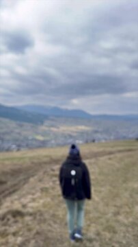 Stunning mountain view enjoyed by visitor wearing a cozy hat on a cloudy day