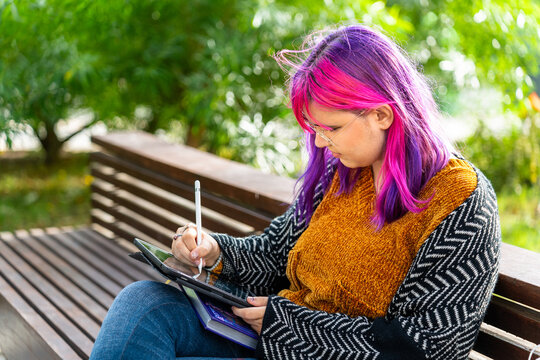 Young designer drawing on tablet in park: body positive, autism awareness