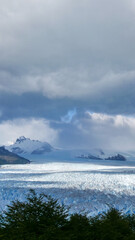 Vertical image of  View of Perito Moreno Glacier with clouds and mountains in the background, Los Glaciares National Park, Argentina