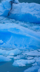 Vertical image of  Close up of blue pieces of ice floating in the water. Los Glaciares National Park, Argentina