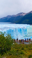 Vertical image of Perito Moreno. Tourists standing at the viewpoint looking a the edge of the Perito Moreno glacier.  Los Glaciares National Park