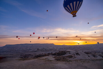 A large number of hot air balloons taking off and floating above the Rose Valley at sunrise, with large balloons in the foreground