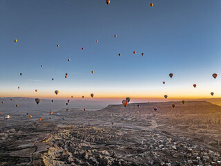  Hundreds of hot air balloons above Love Valley with tall chimney-like rock formations in Cappadocia at sunrise