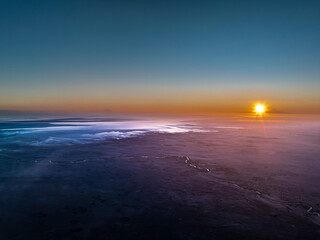Fototapeta premium Aerial view of the black sand desert of Tuz Lake with a winding river at sunrise with violet hues, Turkey
