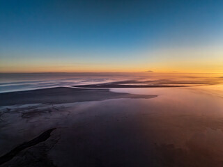 Fototapeta premium Aerial view of black sand shores and shimmering waters of Tuz Lake at sunrise, Turkey